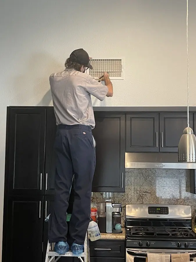 Technician inspecting an air vent during HVAC service in Lyndhurst